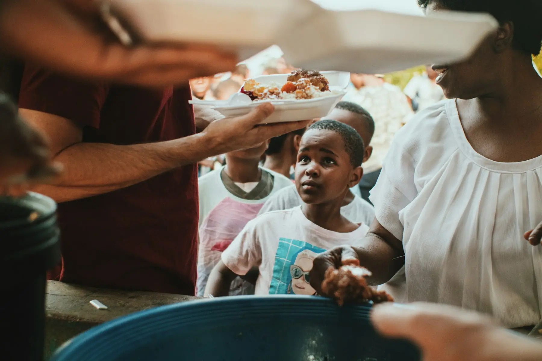 A hot meal being served to a waiting child at a community feeding outreach